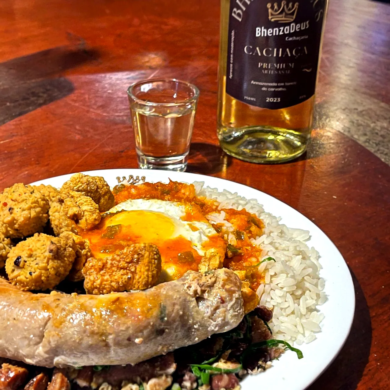 O KAOL BhenzaDeus: arroz, ovo de gema mole, linguiça de pernil e tropeiro, ao lado da cachaça da casa