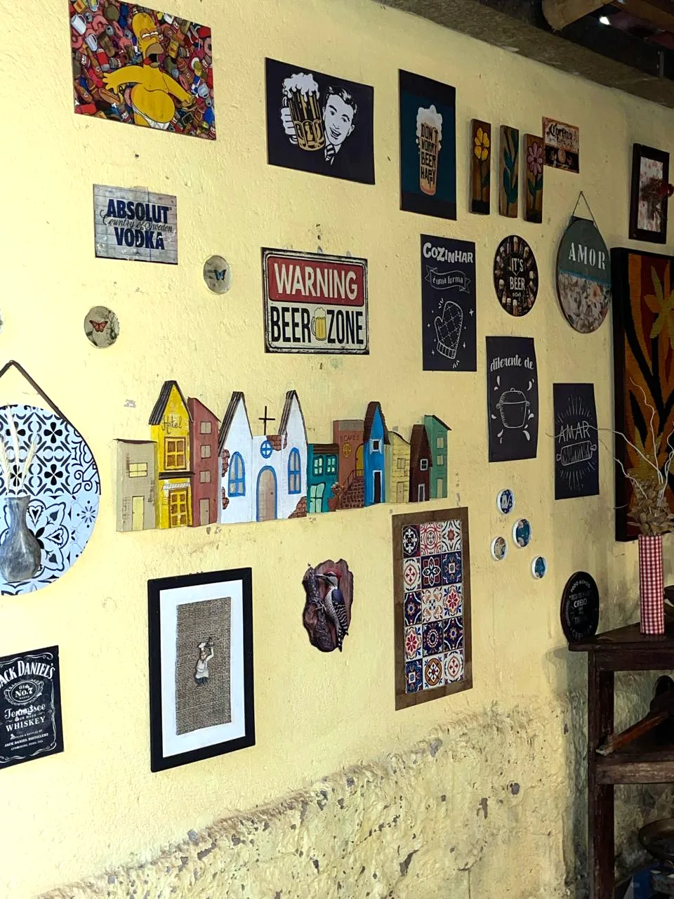 Um canto da parede do salão, com as casinhas pintadas, placas de cerveja e azulejos