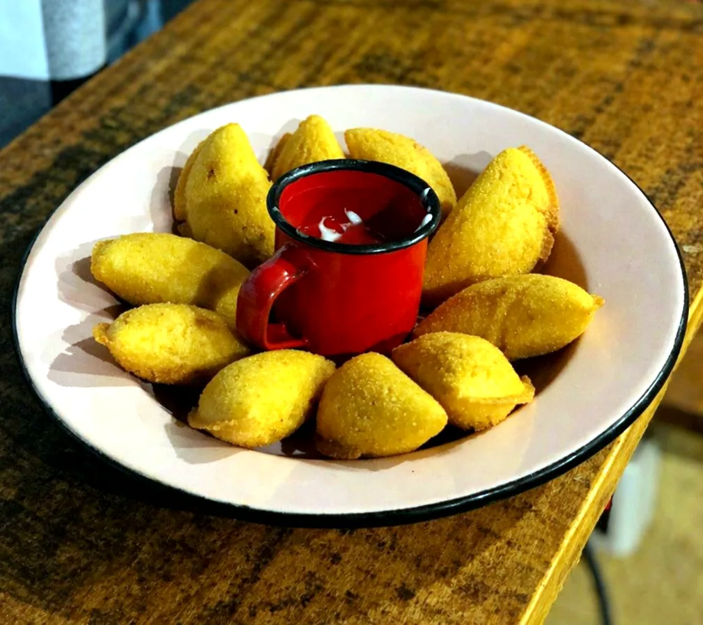 Pastel de angu com uma caneca de molho vermelho no meio do prato