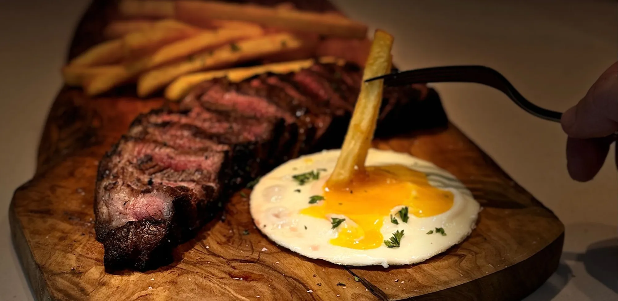 Picanha with a fried egg and fries on a wooden board