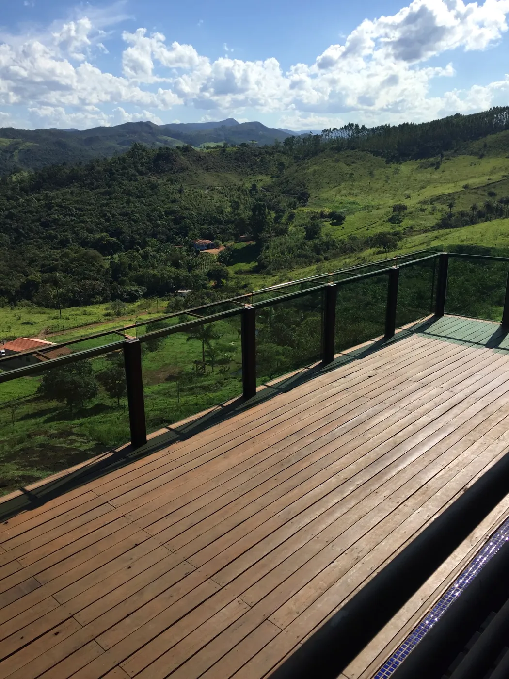 Deck de madeira com guarda-corpo de ferro e a serra verde ao fundo