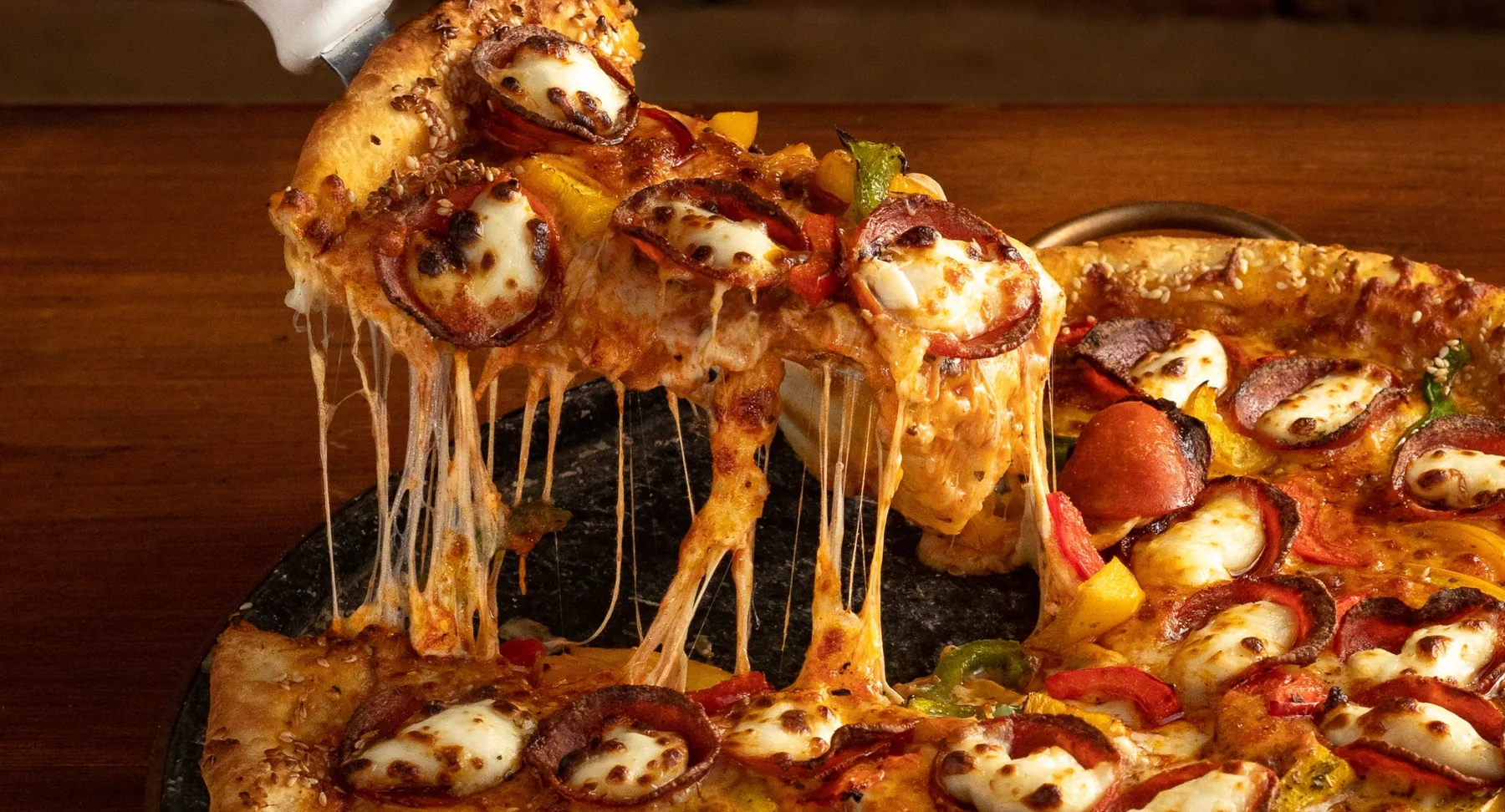 Pizza de pepperoni da Em Cantos, com o queijo esticando na fatia