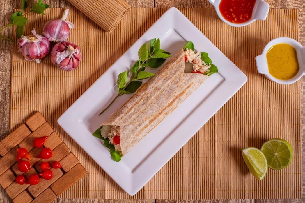 Pão folha enrolado com salada e recheio, servido numa travessa branca