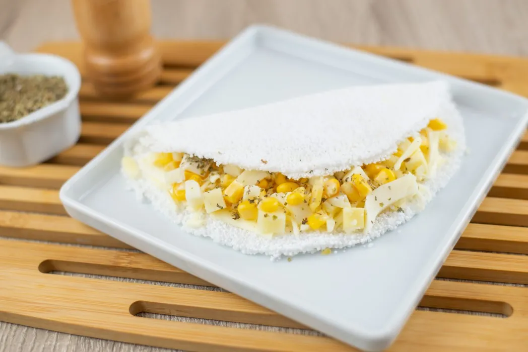 Tapioca recheada com milho e queijo num prato branco