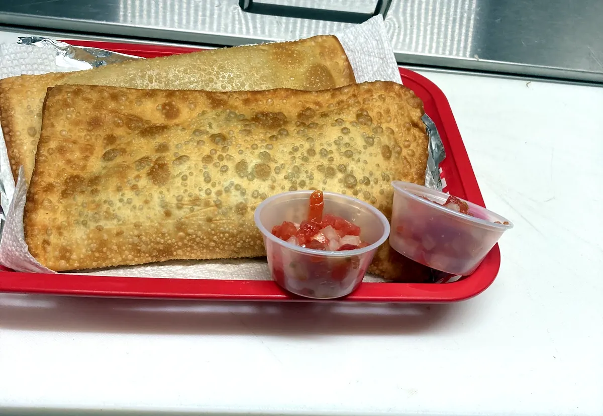Dois pastéis no cesto vermelho, com dois potinhos de vinagrete