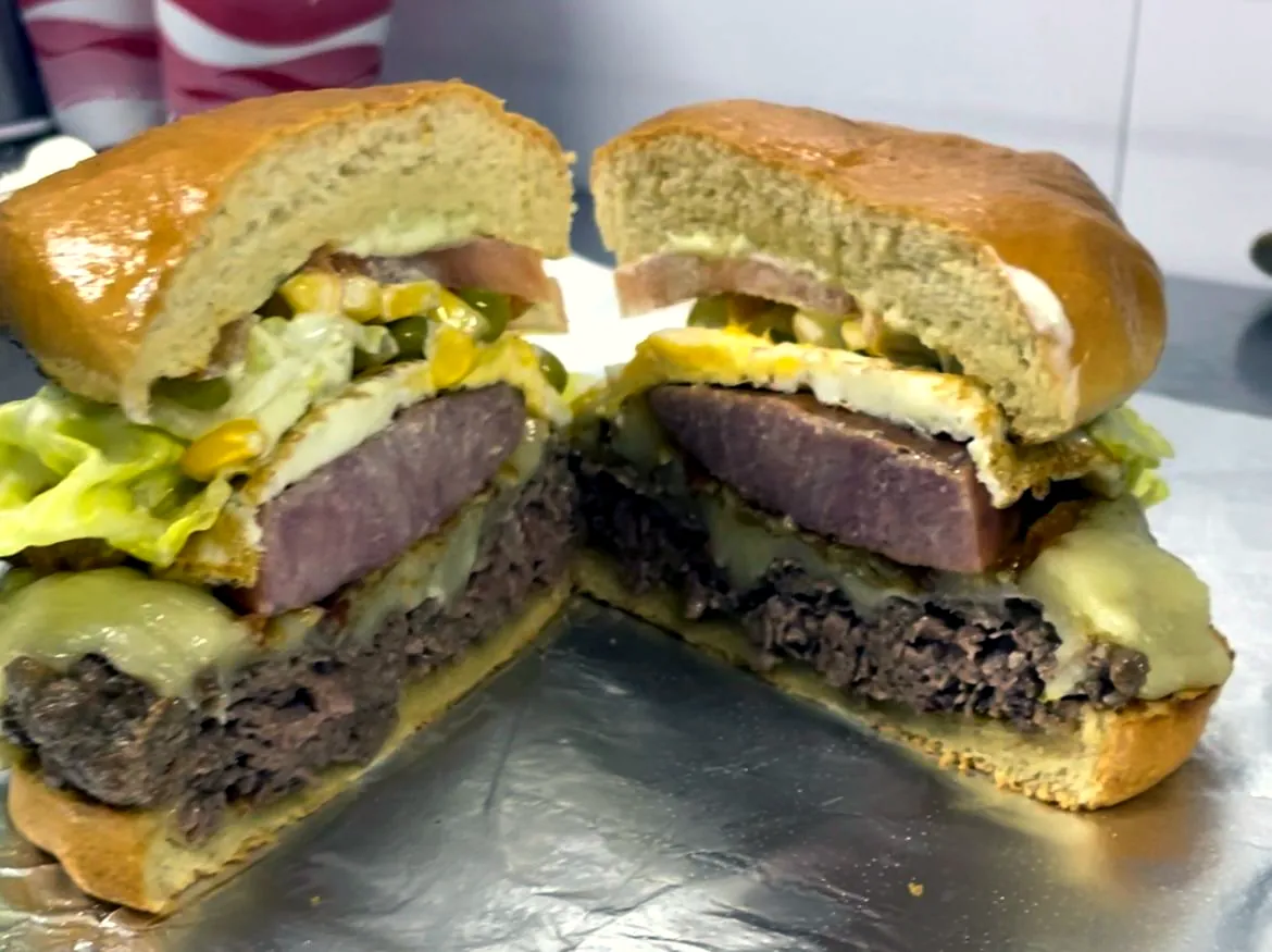 Hambúrguer de picanha cortado ao meio, com queijo, presunto, ovo e milho