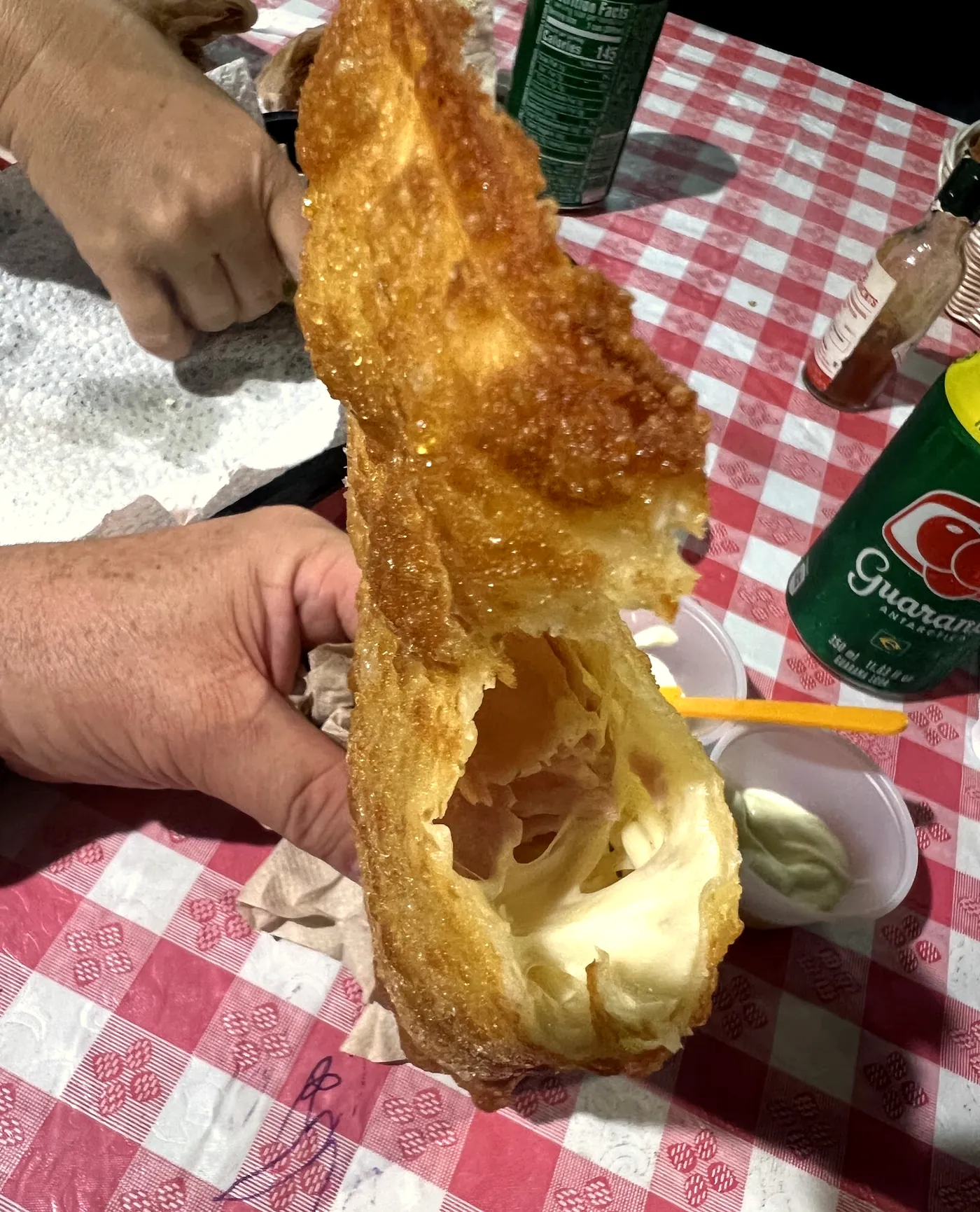 Pastel aberto ao meio, com o queijo derretido puxando
