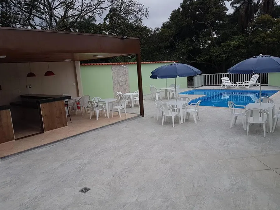 A piscina com as mesas brancas e os guarda-sóis azuis do bar