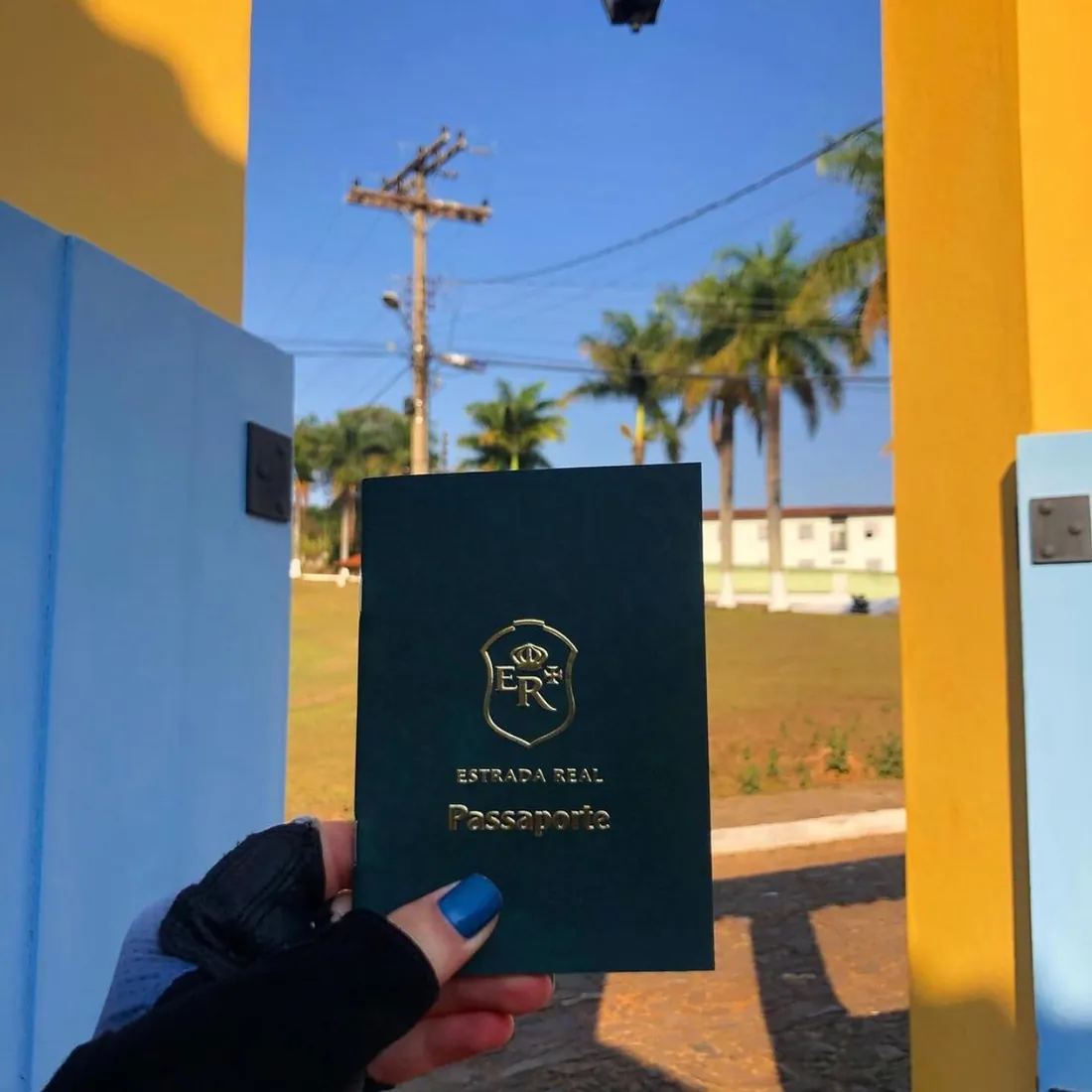 Ciclista segurando o passaporte da Estrada Real na porta da pousada