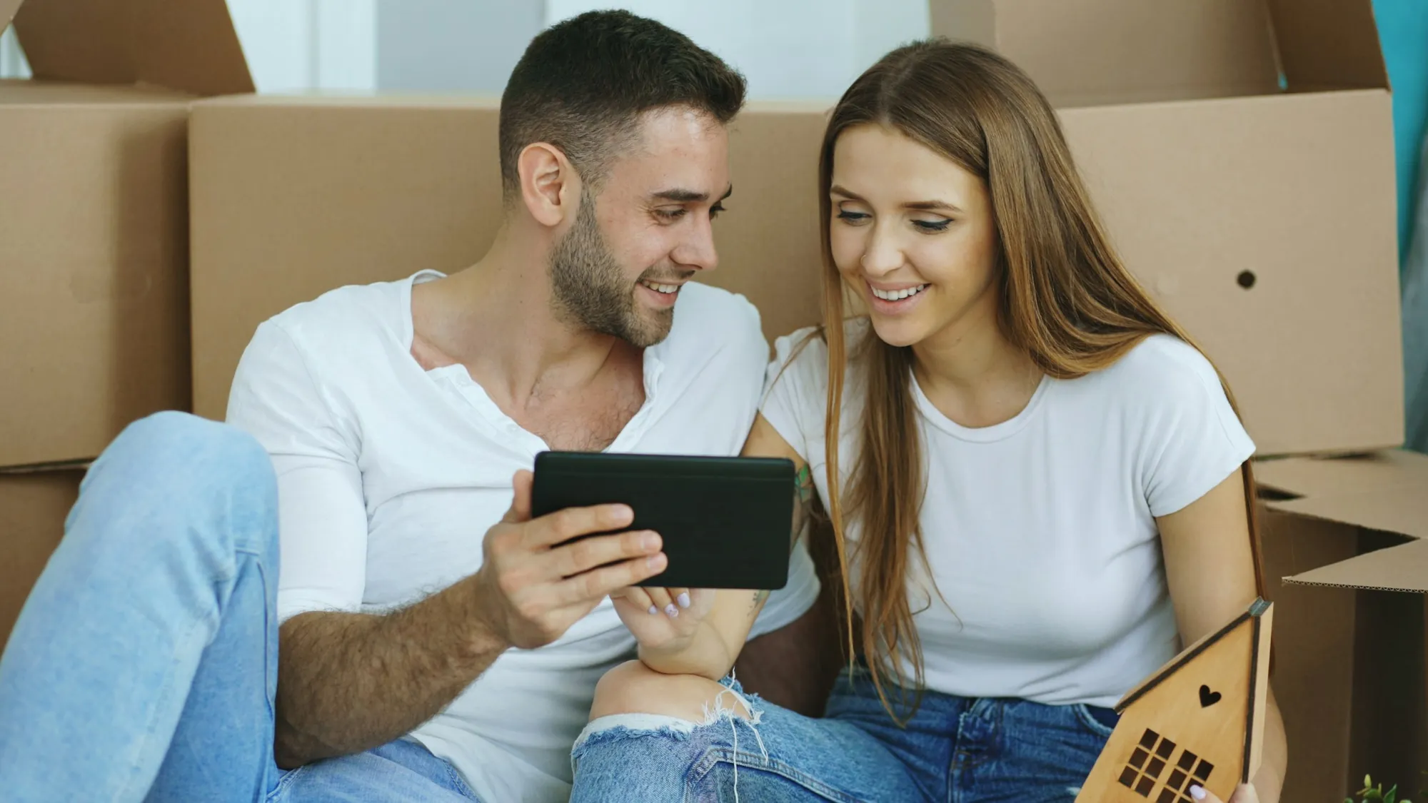Casal recebendo a casa nova, entre caixas de mudança