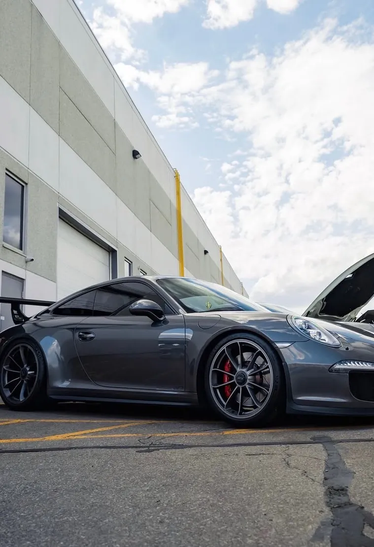 Grey Porsche 911 GT3 with the hood open outside a shop