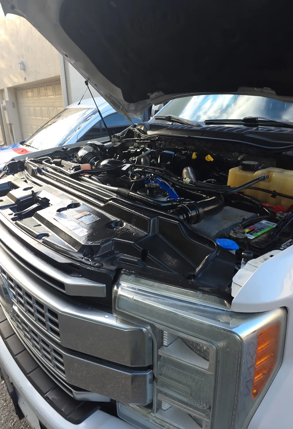 Engine bay of a white Ford Super Duty pickup with the hood up, cleaned