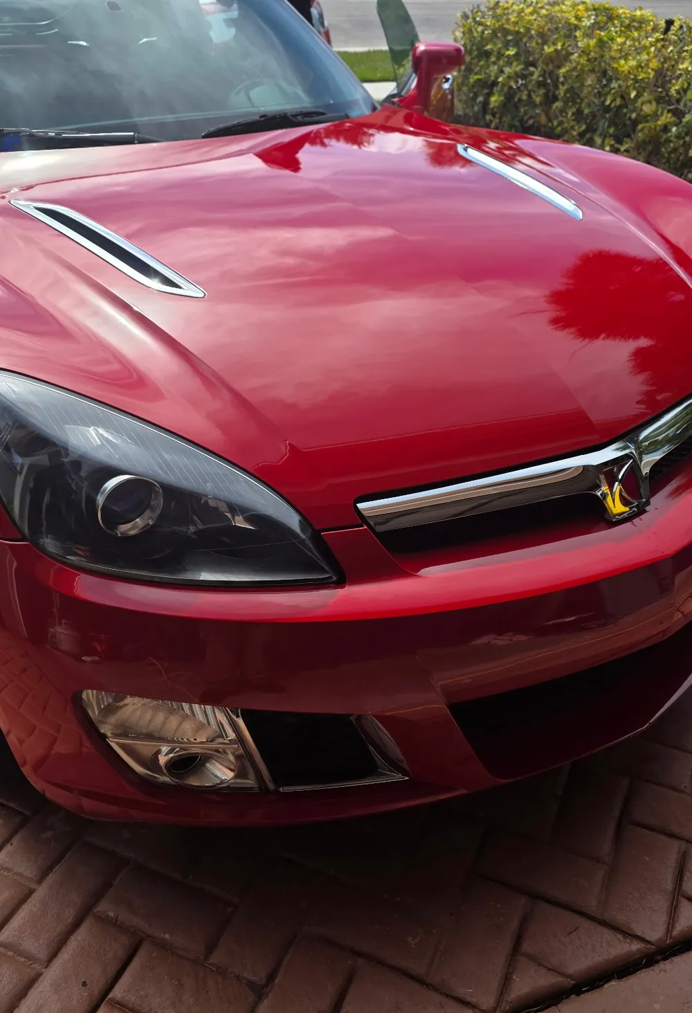 Red Saturn Sky roadster with glossy paint on a brick driveway