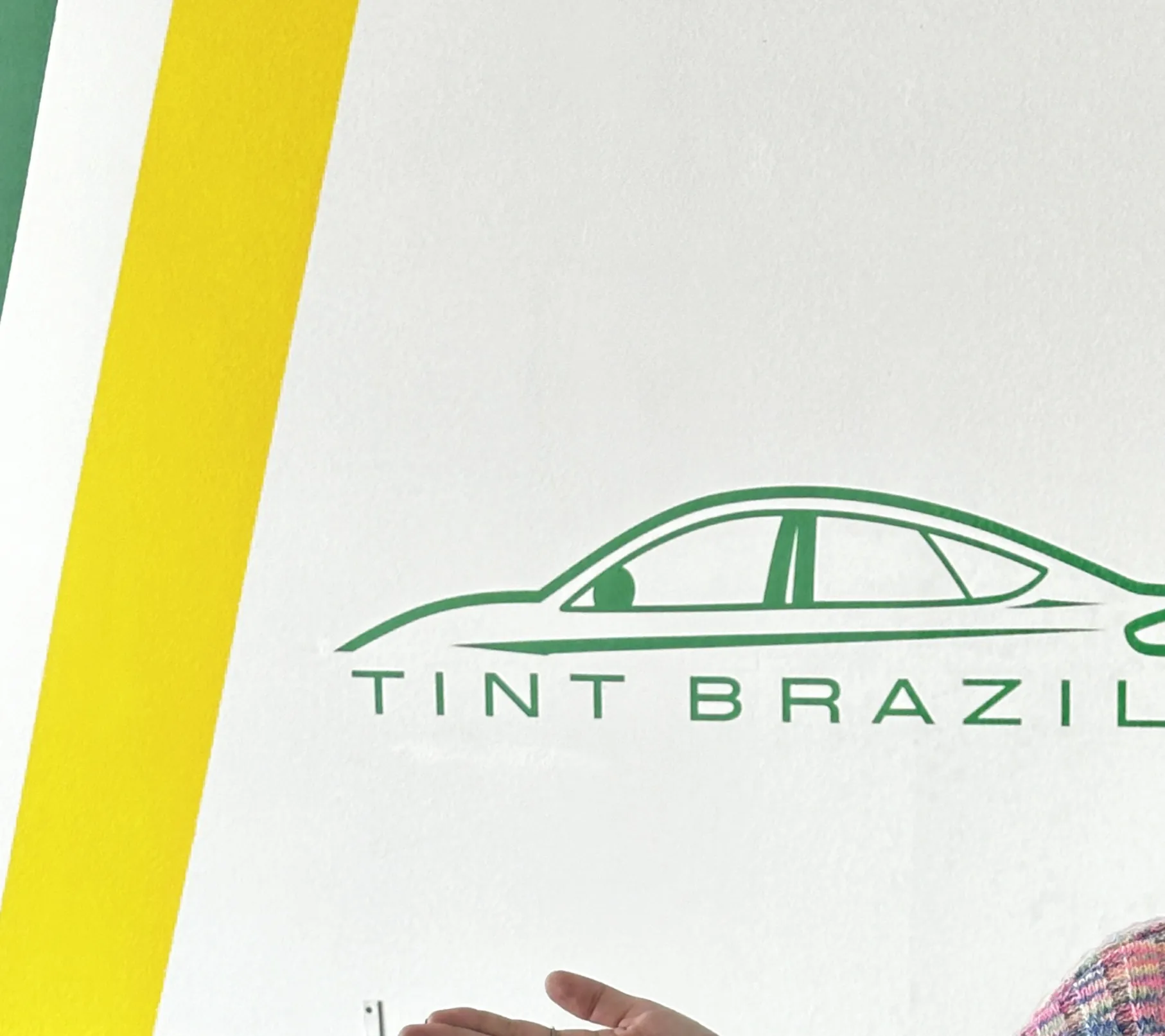Tint Brazil logo on the shop wall with green and yellow stripes